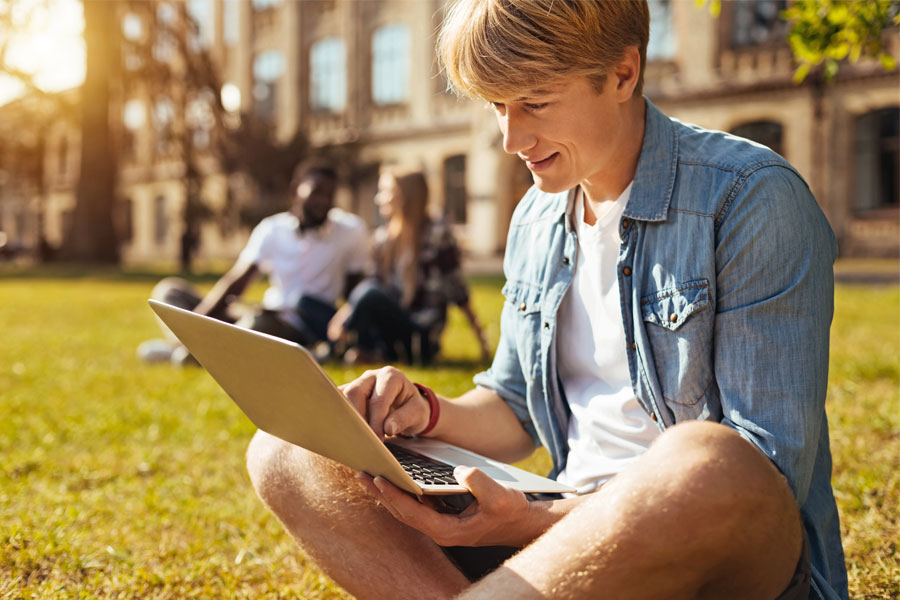 man sitting in the grass on a laptop