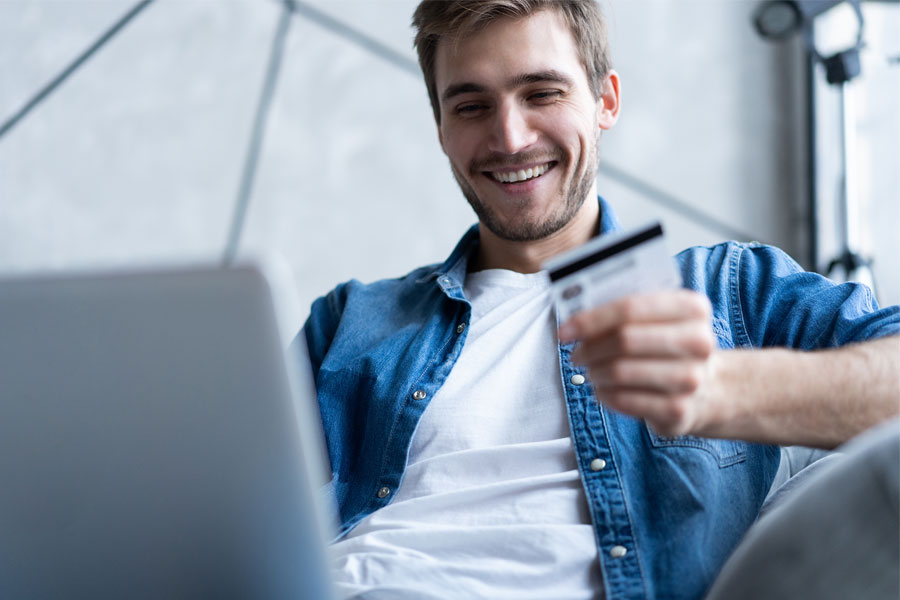 man smiling and looking at credit card