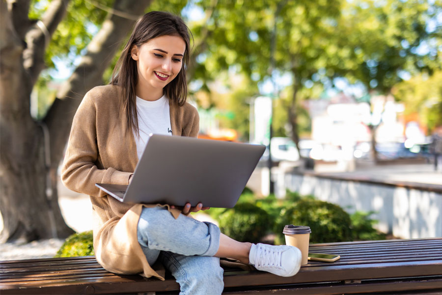woman on laptop outside with coffee